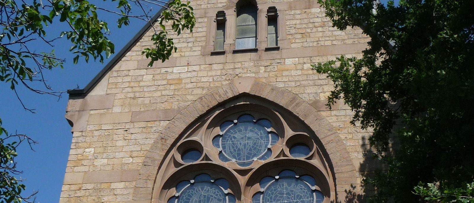 Sandsteingiebel der Pauluskirche mit großem Rosettenfenster und drei schmalen Fenstern darüber